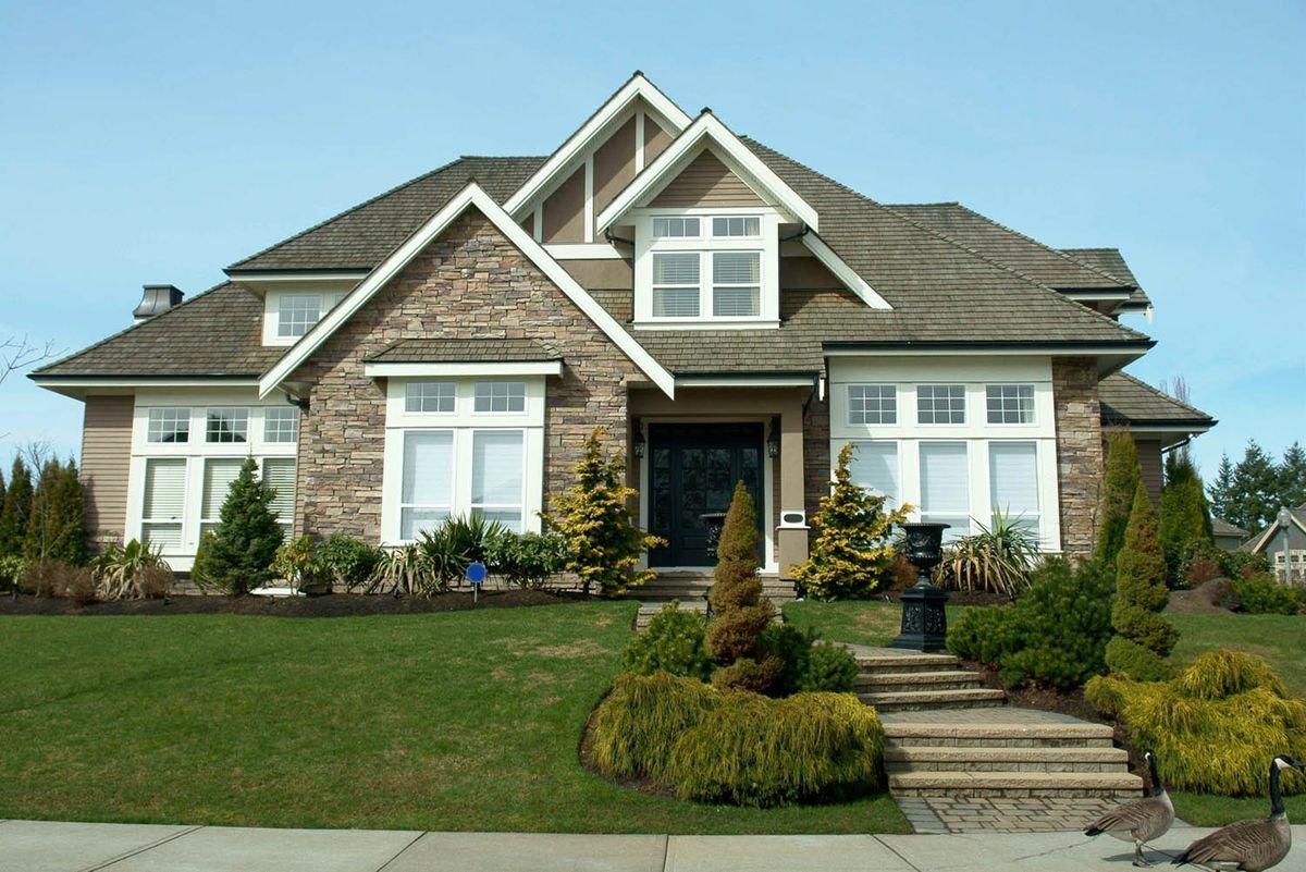 A stone and siding home exterior with new windows and landscaping